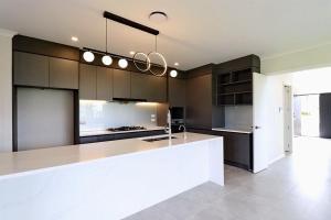 una cucina con ampia isola bianca in una stanza di Extra-Large Brand-New House 8 Bedrooms 6 Bathrooms ad Auckland
