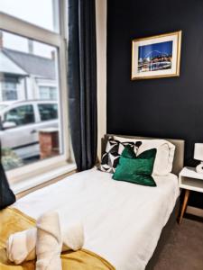 a bed with a green pillow and a window at A&A Luxury Stay Eldon Street in Pallion