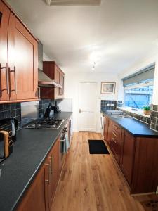 a kitchen with wooden cabinets and black counter tops at A&A Luxury Stay Eldon Street in Pallion