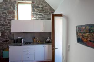 a kitchen with white cabinets and a stone wall at Romantic Ocean Getaway by Slice of Heaven in Jardim do Mar