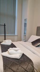 two white towels are sitting on two beds at Kest Cozy Apartment in Leeds! in Leeds