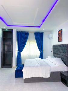 a bedroom with a large bed with blue curtains at D & D Apartments in Abuja