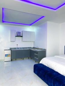a bedroom with a bed and a kitchen with purple lights at D & D Apartments in Abuja