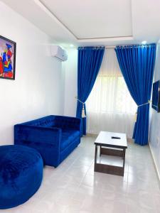 sala de estar con sofá azul y mesa en D & D Apartments, en Abuja