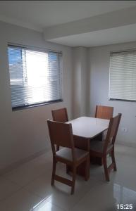 a dining room with a table and chairs and two windows at VS HOSPEDAGEM in Cascavel