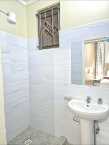 uma casa de banho branca com um lavatório e uma janela em 3 BDR Luxurious Villa in Milimani Kisumu em Kisumu