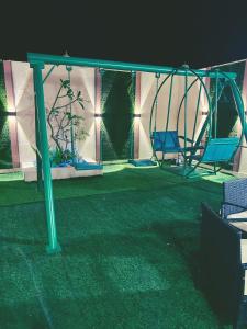 un parque infantil con columpio en un patio en فيلا الوريك Villa Al Warik, en Umm Lajj