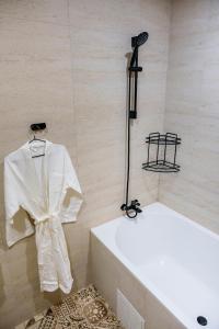 a bathroom with a white robe hanging on a wall at Dami Almaty Hotel in Almaty