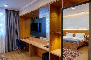 a hotel room with a bed and a television at Dami Almaty Hotel in Almaty