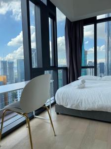 a bedroom with a bed and a chair in front of windows at Star Residence Klcc By M&T in Kuala Lumpur