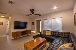 a living room with a leather couch and a flat screen tv at NEW! Stylish & Cozy Sea Grape near Beach & Flagler in New Smyrna Beach