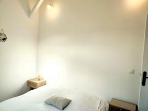 a bedroom with a white bed and a white wall at Appart de charme aux pieds des remparts, terrasse in Guérande