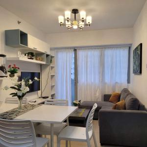 マニラにあるQE811 Cozy 1 BR & Sofa Bed Free WiFi & Pool Accessのテーブルとソファのあるリビングルーム