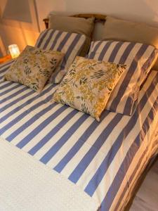 two beds with blue and white striped sheets and pillows at La petite maison de Coline in Réville