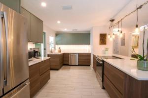 a large kitchen with wooden cabinets and white counter tops at TOP RATED! Buddha's Bungalow, near Flagler & Beach in New Smyrna Beach +9 photos
