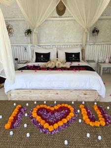 Una cama con un corazón hecho de flores. en Tropical Glamping Nusa Penida - Private Romantic Seaside Bungalow Diamond Beach, en Nusa Penida