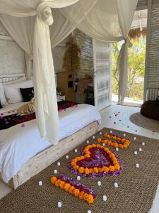 Una cama con un ramo de flores en el suelo en Tropical Glamping Nusa Penida - Private Romantic Seaside Bungalow Diamond Beach, en Nusa Penida