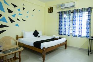 - une chambre avec un lit et une chaise dans l'établissement Reunion Amity, à Udupi