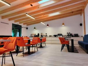 a restaurant with orange chairs and tables and a kitchen at Hotel Aldi in Gura Humorului