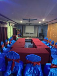 una sala conferenze con tavoli e sedie rossi e schermo di Namaste Hotel a Ataria
