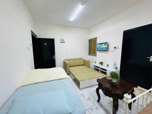 a bedroom with a bed and a couch and a table at Comfy Studio Apartment in Abu Dhabi