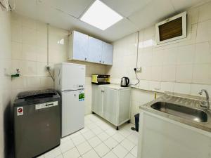 a small kitchen with white appliances and a sink at Comfy Studio Apartment in Abu Dhabi