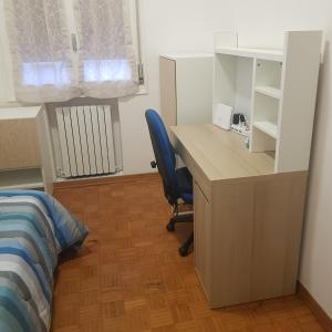 - une chambre avec un bureau et une chaise bleue dans l'établissement Casa frà i Pini, à Imola