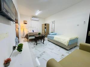 a room with a bed and a desk and a tv at Comfy Studio Apartment in Abu Dhabi
