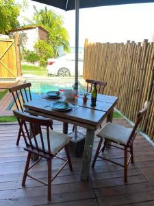 a wooden table with two chairs and an umbrella on a patio at Casa beira mar com picina em Milagres - Verde Mar in Passo de Camarajibe