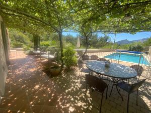 eine Terrasse mit einem Tisch, Stühlen und einem Pool in der Unterkunft Les Dentelles in Beaumes-de-Venise