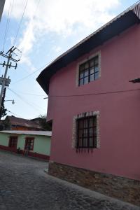 um edifício cor-de-rosa com janelas numa rua em Hotel California em Mineral del Monte