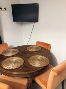 une table en bois avec quatre chaises et une télévision murale dans l'établissement Joli T2 à Dinard coeur de Saint Enogat, 200m de la plage, à Dinard