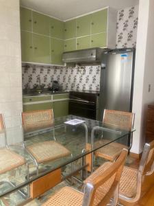 uma cozinha com uma mesa de vidro com cadeiras e um frigorífico em Apartamento no Hotel Quitandinha 40 em Petrópolis