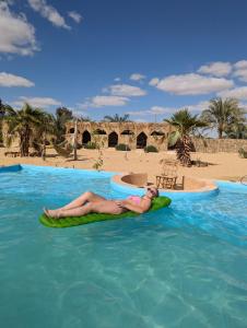 un hombre tendido en una balsa en el agua en un resort en Cafour House Siwa - Hot Spring en Siwa