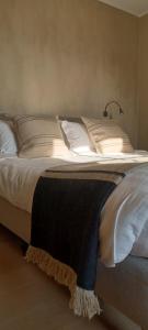 a bed with white pillows and a black blanket on it at LA BELLE IDEE in Nokere