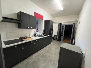 uma cozinha com armários pretos e uma caixa vermelha na parede em Studio calme tout confort em Dions