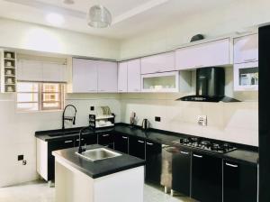 una cocina con armarios en blanco y negro y fregadero en Isu Vista Royale Shortlet Osapa Lekki Lagos, en Lekki