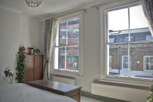 a bedroom with two windows and a bed and a table at The Rose Terrace - 2BD Home Kentish Town in London