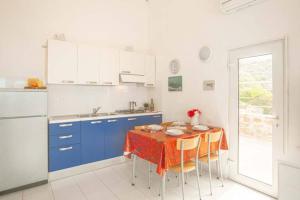 une cuisine avec des placards bleus et une table avec des chaises dans l'établissement Giglio Verde 2, à Isola del Giglio