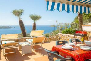 un patio avec une table et des chaises et l'océan dans l'établissement Giglio Verde 2, à Isola del Giglio