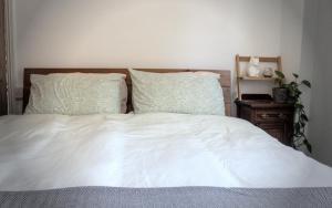 a bedroom with a white bed with two pillows at The Rose Terrace - 2BD Home Kentish Town in London