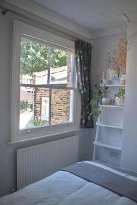 a bedroom with a window and a bed and a shelf at The Rose Terrace - 2BD Home Kentish Town in London