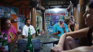 een groep mensen die rond een tafel zitten met bierflessen bij Roby Homestay in Kuta Lombok