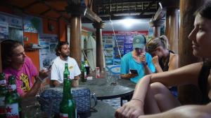 un grupo de personas sentadas alrededor de una mesa con botellas de cerveza en Roby Homestay, en Kuta Lombok