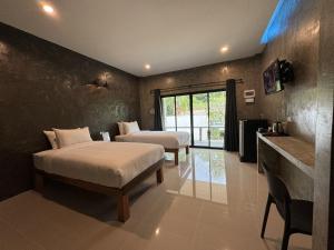 1 dormitorio con 2 camas, mesa y lavamanos en BAAN CHAINARONG, en Ko Lanta