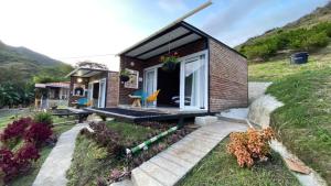 ein kleines Backsteinhaus mit einer Veranda auf einem Hügel in der Unterkunft Cabañas “Pacha Mama” in Roldanillo