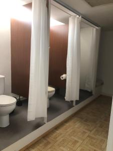 baño con 2 aseos y cortinas blancas de ducha en Urban rest zone and coworking, en Arrecife