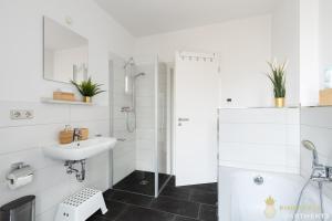 een witte badkamer met een wastafel en een douche bij Pineapple Apartments Dresden Zwinger VIII - 85 qm - 1x free parking in Dresden