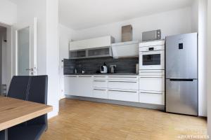 een keuken met witte apparatuur en een houten vloer bij Pineapple Apartments Dresden Zwinger VIII - 85 qm - 1x free parking in Dresden