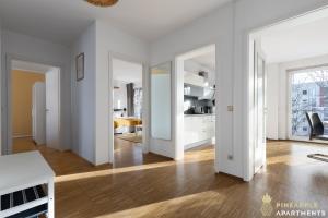 een woonkamer met witte muren en een houten vloer bij Pineapple Apartments Dresden Zwinger VIII - 85 qm - 1x free parking in Dresden